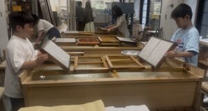 いの町紙の博物館で紙漉き体験をする小学生