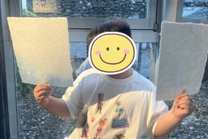 紙漉き体験で完成した和紙そ持つ小学生